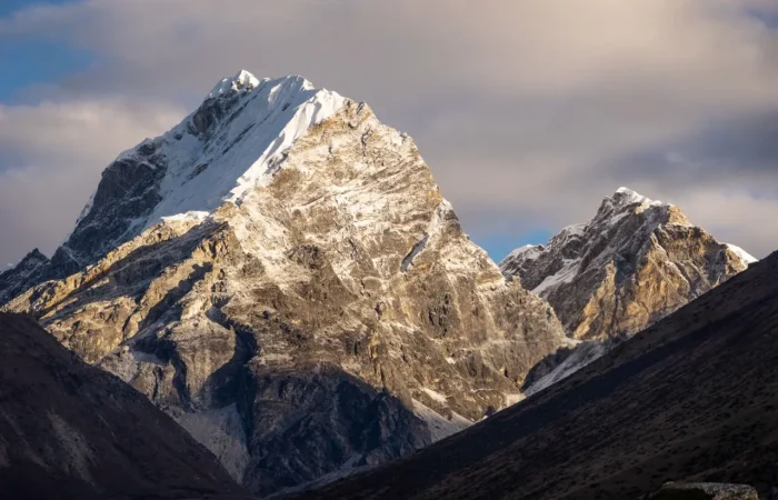 a snowy mountain tops with a cloudy sky