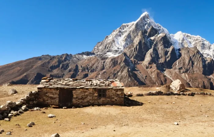 Wide-angle view of Lobuche East Peak amidst the Himalayan range, with dramatic peaks and glaciers under a vibrant blue sky.