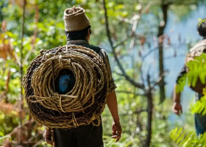 a man carrying a large bundle of rope