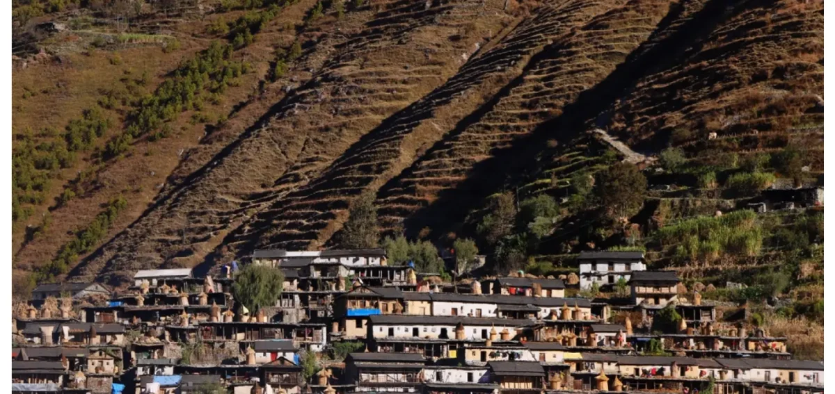 Aerial view of Taksera, Nepal, a terraced village in East Rukum, with traditional stone houses and haystacks, labeled with the text "Taksera, Nepal: Hidden Gem of East Rukum," reflecting the landscape around 1950 (2006-2007 BS).