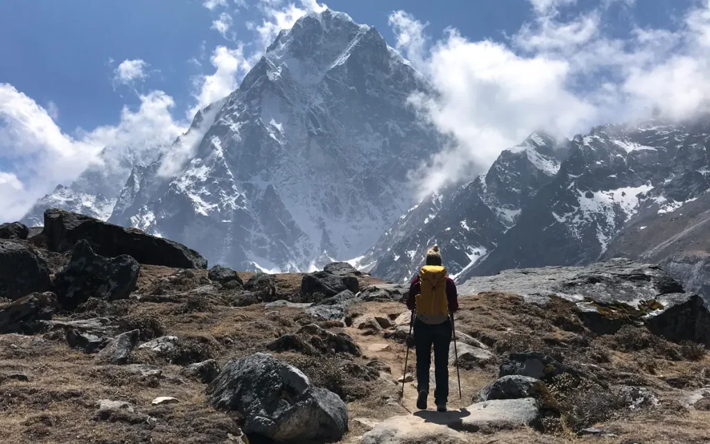 Solo trekker with backpack crossing high mountain pass on Nepal trek challenge with dramatic Himalayan backdrop