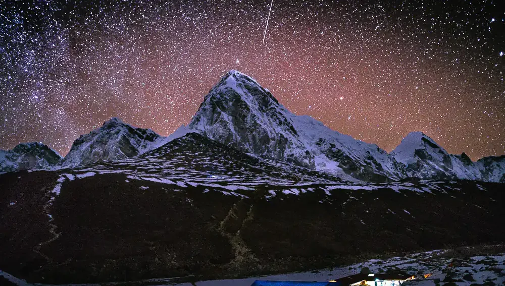 Above snow-capped Himalayan peaks close to Gorakshep on Nepal's Everest Base Camp trail is a starry night sky.