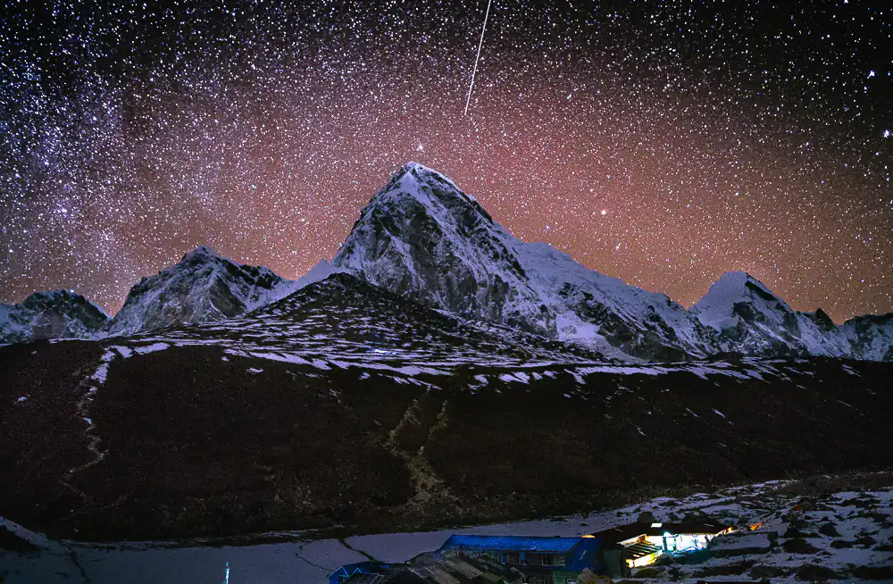 Above snow-capped Himalayan peaks close to Gorakshep on Nepal's Everest Base Camp trail is a starry night sky.
