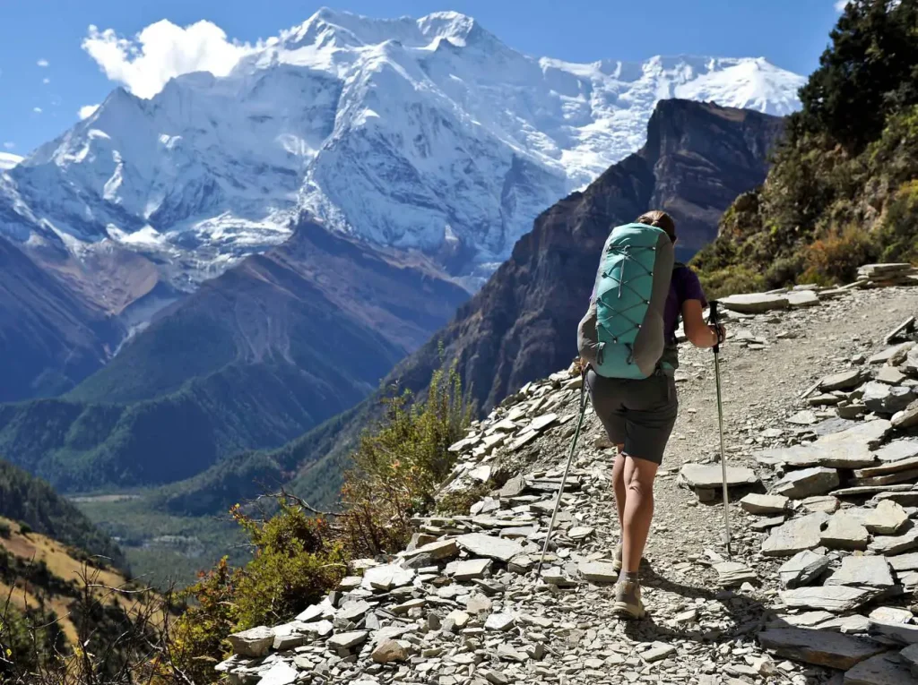 With views of the mountains in the distance, a female hiker strolls along the Annapurna Circuit trail near Manang.