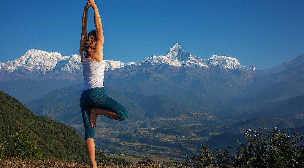Girl practicing yoga pose with Himalayan mountain view at a luxury yoga retreat in Nepal