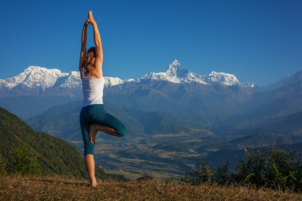 Girl practicing yoga pose with Himalayan mountain view at a luxury yoga retreat in Nepal