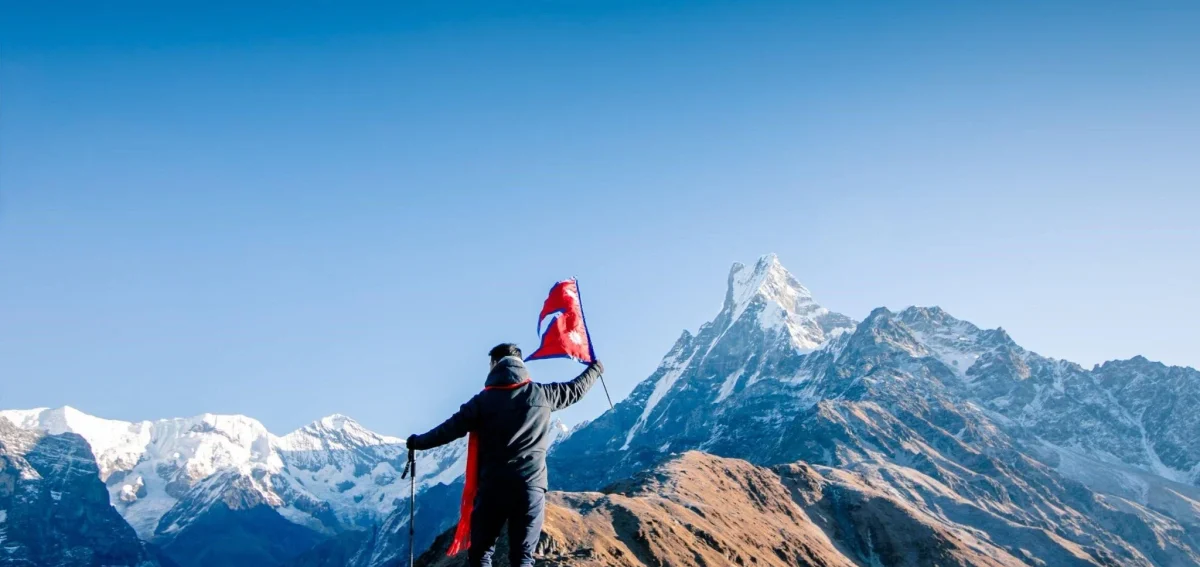 Trekker holding Nepali flag in the Himalayas