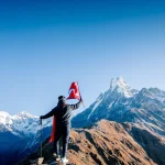 adventures in nepal Trekker holding Nepali flag in the Himalayas