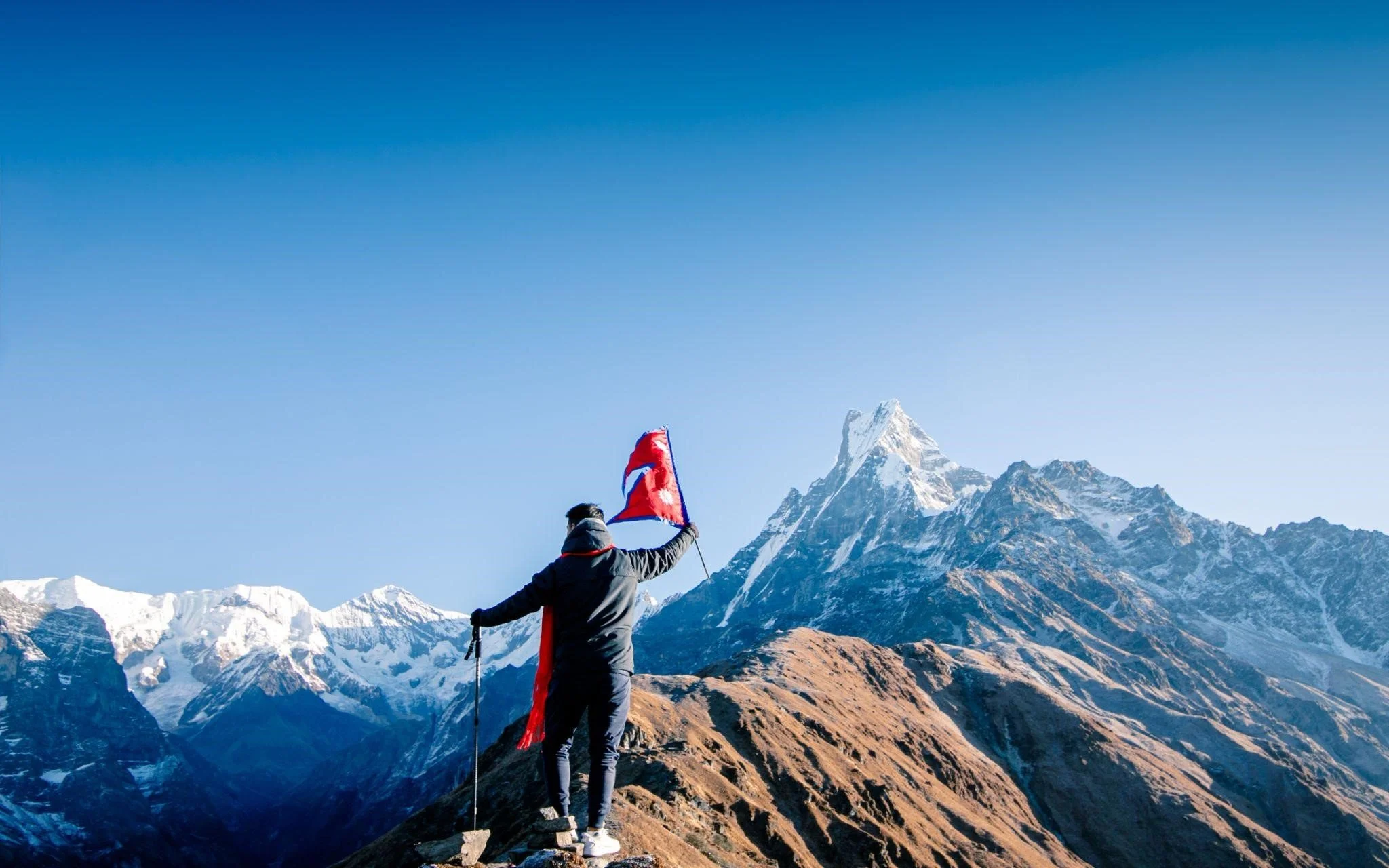 adventures in nepal Trekker holding Nepali flag in the Himalayas