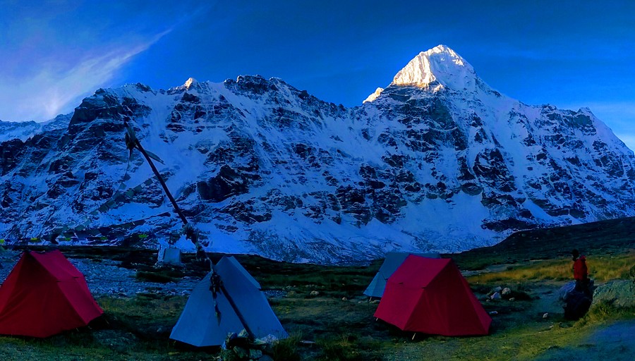 Camping tents set below the towering Himalayan peaks in the Kanchenjunga region, representing one of the most challenging treks in Nepal.