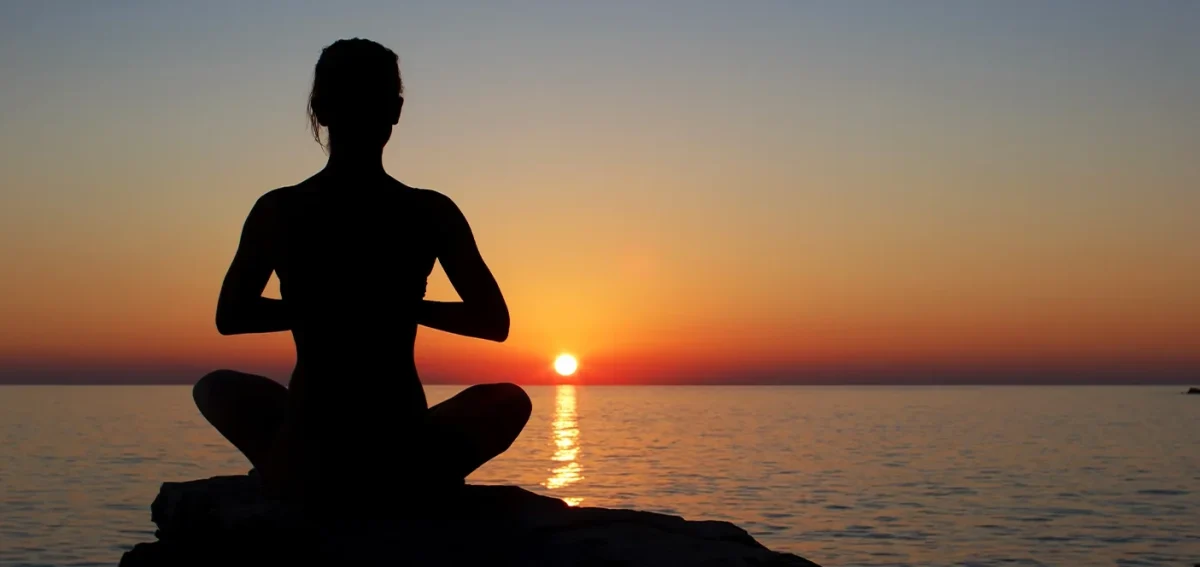 Person practicing sunset meditation in the mountains while preparing for yoga retreat Nepal