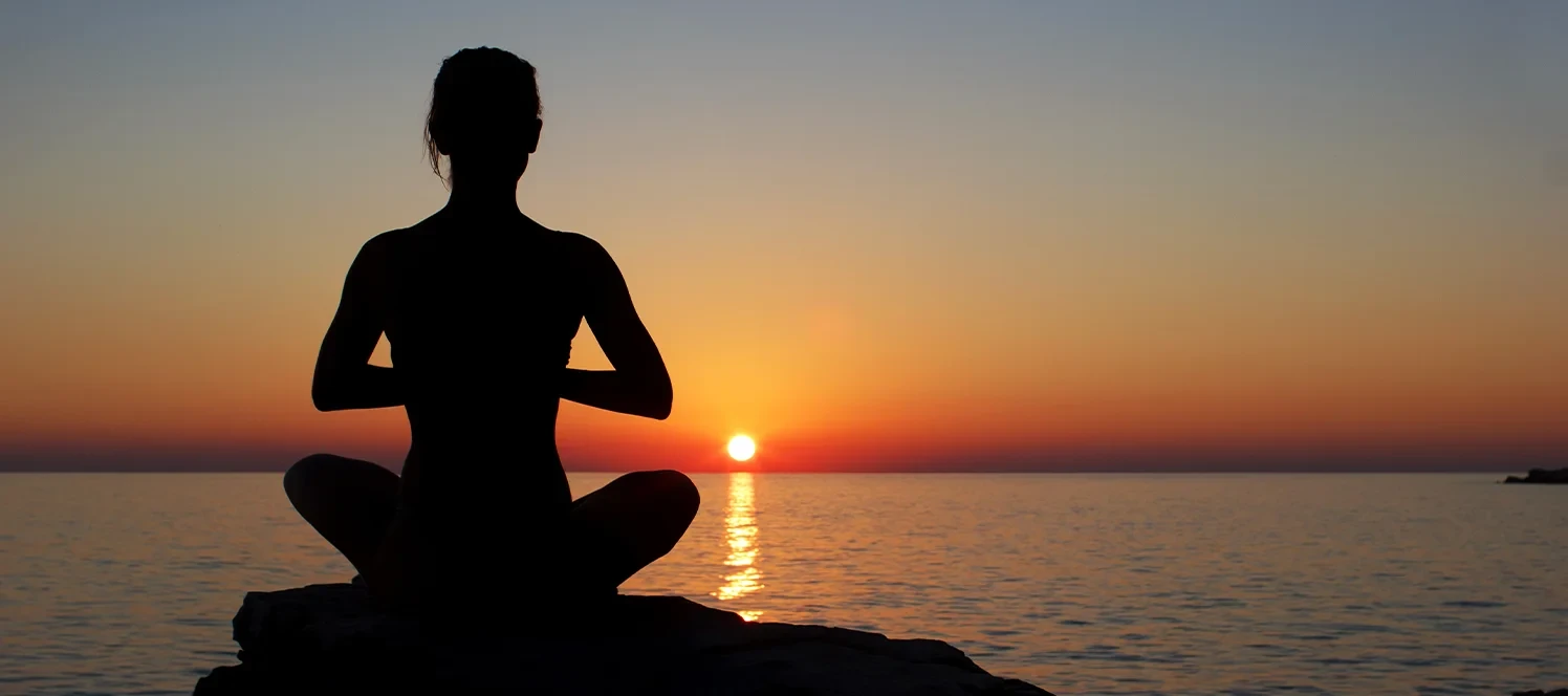 Person practicing sunset meditation in the mountains while preparing for yoga retreat Nepal