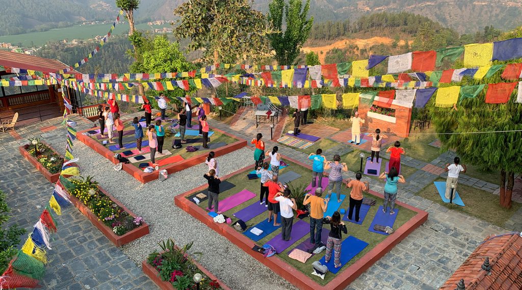 Group of travelers practicing yoga outdoors in the Himalayas at affordable yoga retreats in Nepal