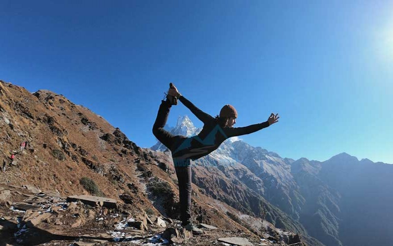 Girl practicing yoga pose with Himalayan mountain views while preparing for yoga retreat Nepal