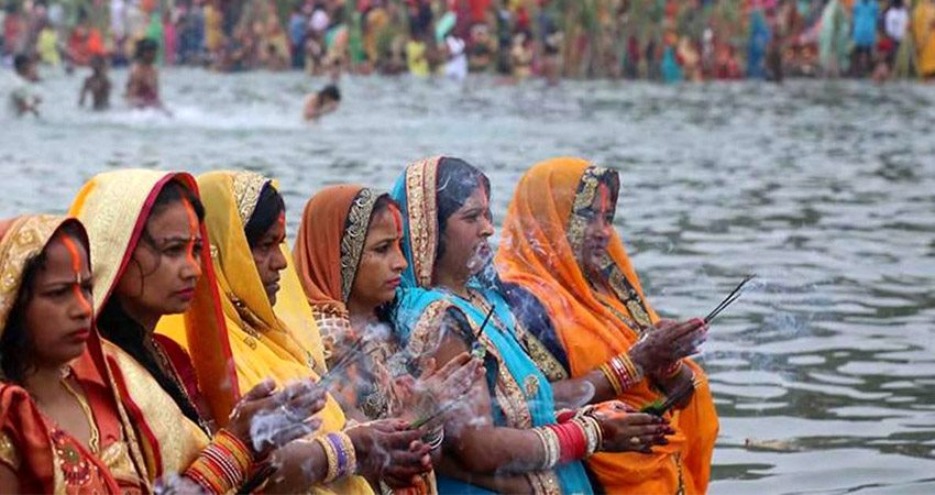 Women performing rituals during Chhath Puja as part of a Kathmandu Festival Tour, offering prayers by the riverside in Nepal