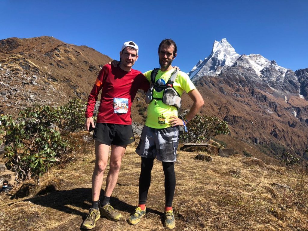 Two trail runners with Machhapuchhre in the background exploring the best trail running routes and altitudes in Nepal