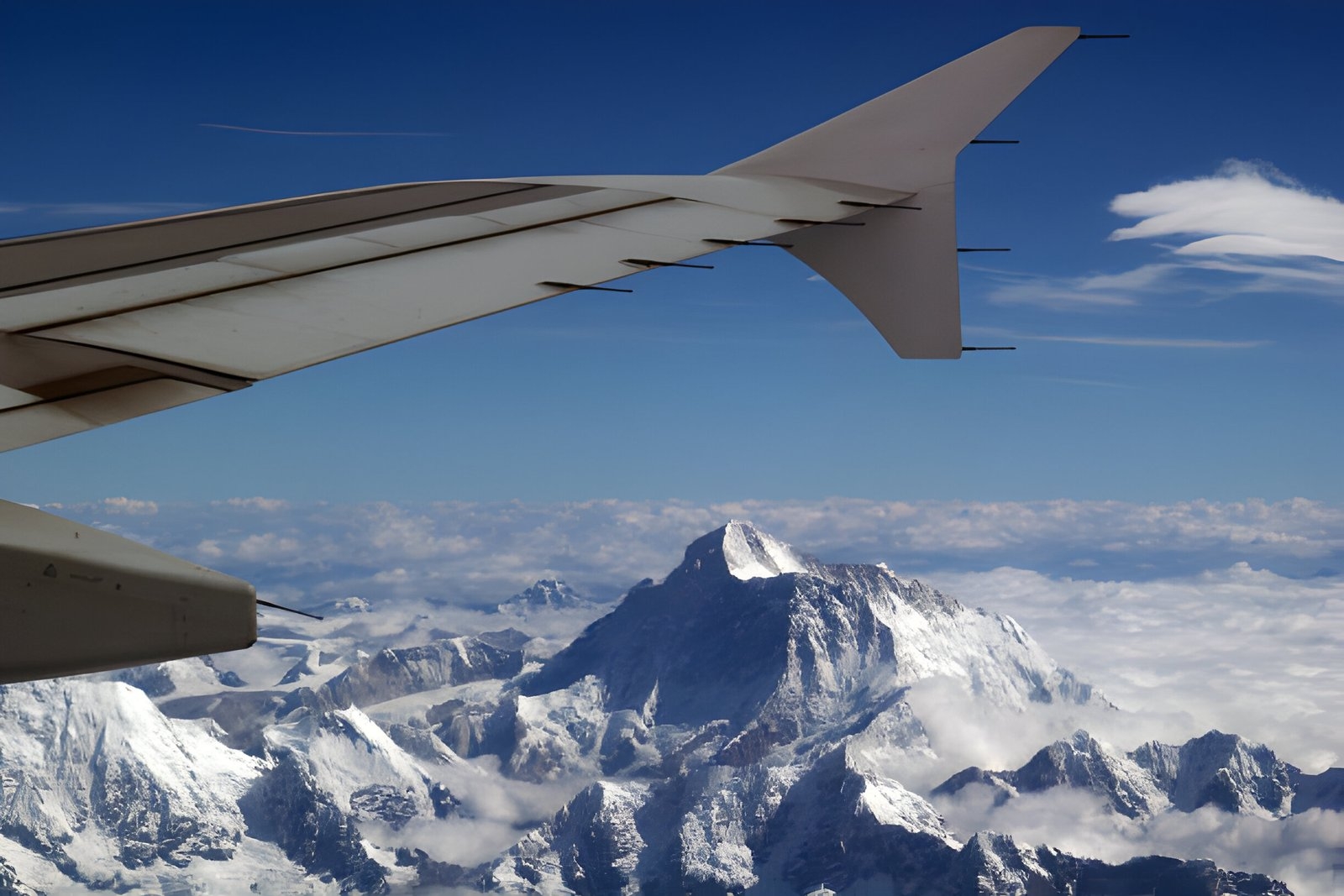 Scenic view of Mount Everest and surrounding Himalayan peaks from a flight to Everest Base Camp, with snow-capped mountains visible through the airplane window.