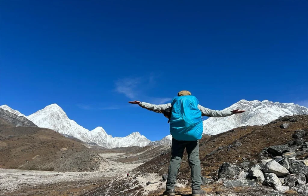 Trekker posing with Mount Everest views during Everest Base Camp trek in autumn, highlighting EBC Spring vs Autumn seasonal differences