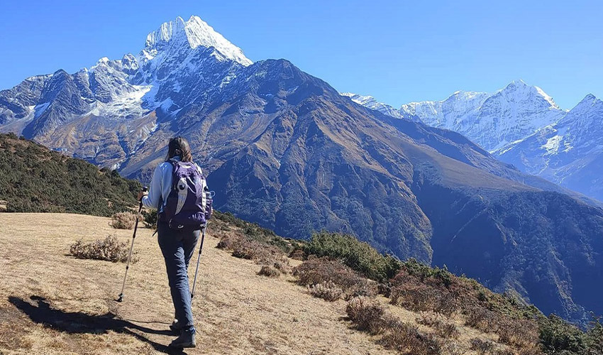 Trekker walking along Himalayan trail with panoramic Kanchenjunga mountain views during Kanchenjunga Circuit Trek, showcasing off-the-beaten-path trekking in Nepal