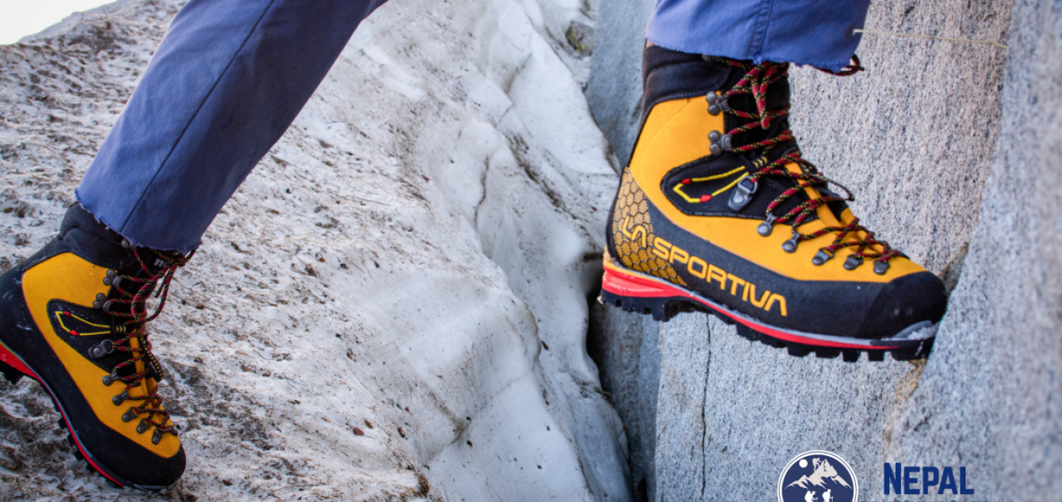 Trekker walking on Himalayan trail wearing La Sportiva Nepal Evo GTX mountaineering boots during high altitude trekking in Nepal with rocky terrain and alpine conditions