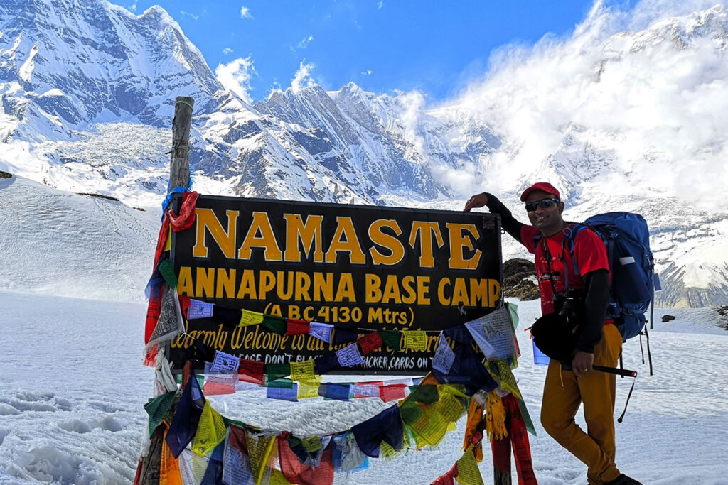 Trekker posing at the Annapurna Base Camp signboard during Annapurna trekking in Nepal