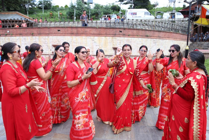Nepali women in traditional red saris dancing and singing during the Teej festival at Pashupatinath Temple in Kathmandu.