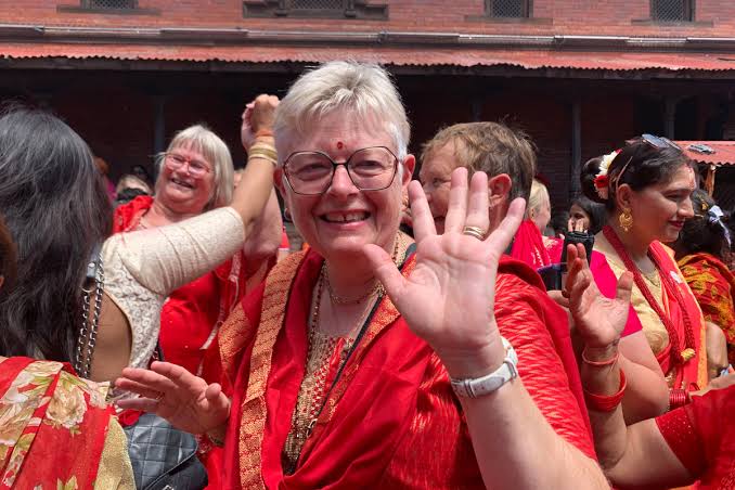 Travelers wearing traditional red saris and participating in the Teej festival alongside local women in Nepal.