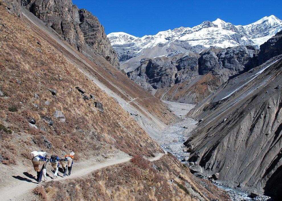 Trekkers walking along a scenic mountain trail during the cheapest trek in Nepal.