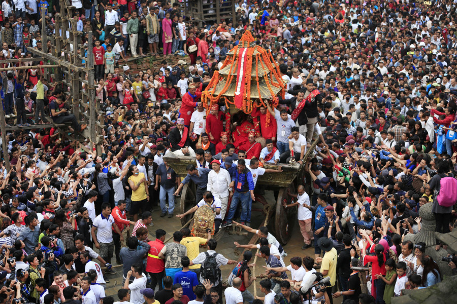 Locals pulling the heavy wooden chariot of the Living Goddess Kumari through the historic streets of Kathmandu during Indra Jatra