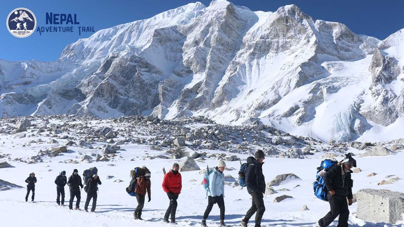 Trekkers navigating the snowy, high-altitude trail during the Larkya La Pass crossing on the Manaslu circuit trek history route.