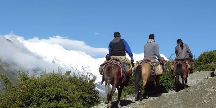 Trekkers riding horses across a remote trail, showcasing why securing a proper nar phu valley trek permit is necessary for exploring this rugged region.