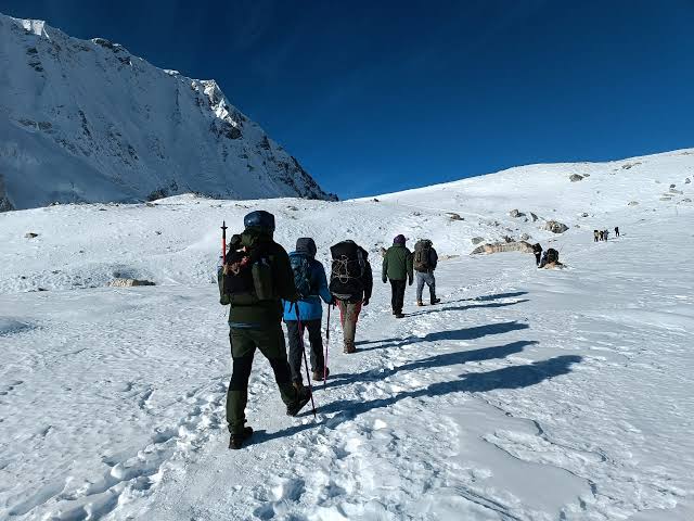 Trekkers walking along a scenic mountain path with backpacks during the Manaslu circuit trek history route.