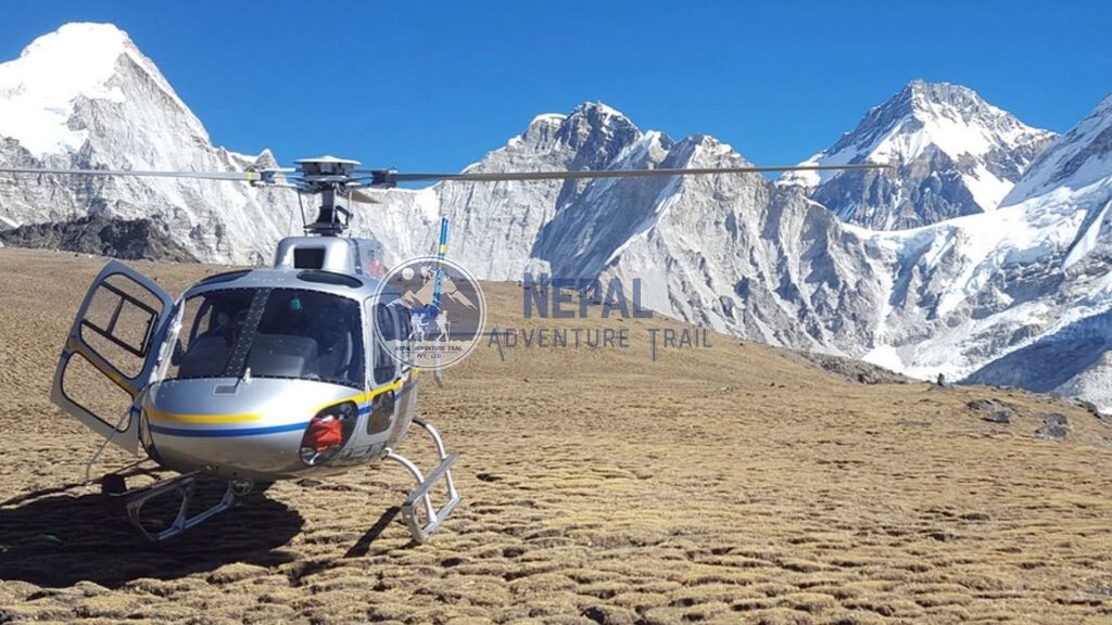 A sleek silver helicopter parked on a mountain helipad, highlighting the Everest Base Camp Trek with Helicopter Return experience amidst Himalayan peaks.