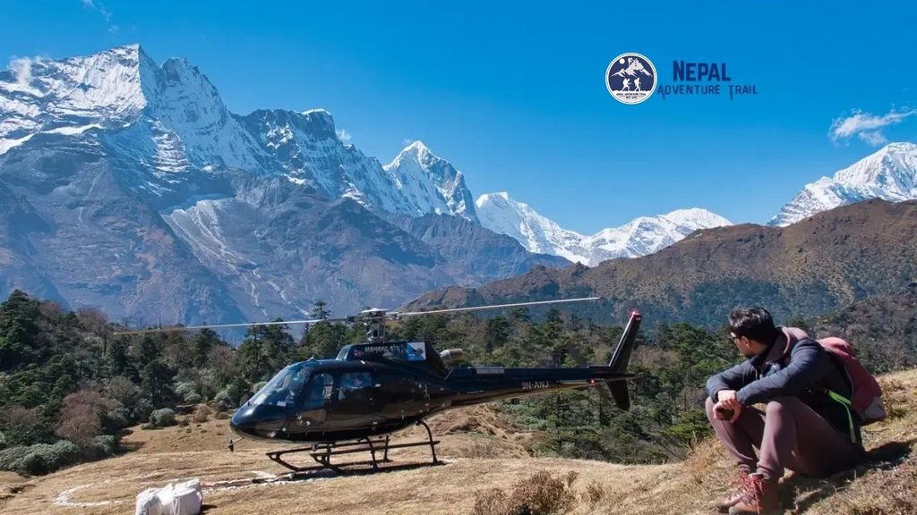 A trekker looking up at a helicopter arriving on a mountain trail during an Everest Base Camp Trek with Helicopter Return.